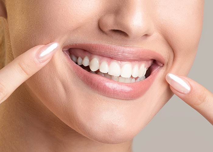 Close-up of smiling woman pointing to her teeth, illustrating the concept of Ozempic mouth side effect from weight-loss substance. Close-up of smiling woman pointing to her teeth, illustrating the concept of Ozempic mouth side effect from weight-loss substance.
