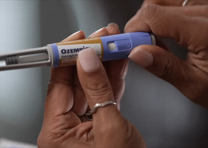 Hands holding an Ozempic injection pen, highlighting concerns around Ozempic teeth as a side effect of weight loss meds.