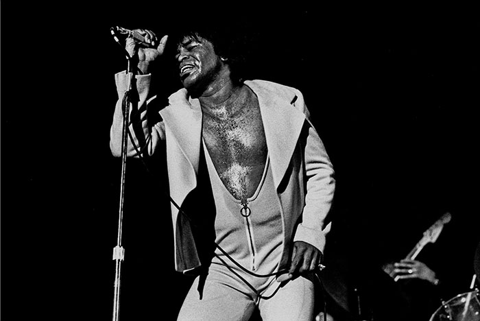 Black and white photo of a male singer passionately performing on stage, highlighting celebrity fame and legacy.