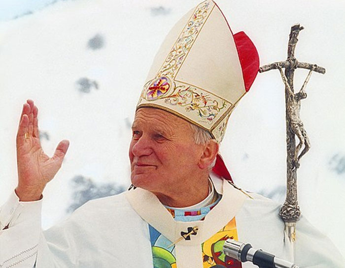Religious leader in ceremonial attire holding a crucifix staff, symbolizing influence and reverence after passing.