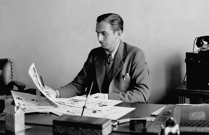 Young man in a suit reviewing papers at a desk, representing Steve Jobs and celebrities praised after passing.