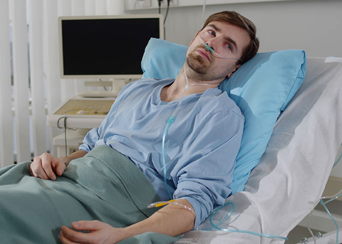 Male patient lying in hospital bed with oxygen tube, reflecting chilling final words doctors and nurses heard.