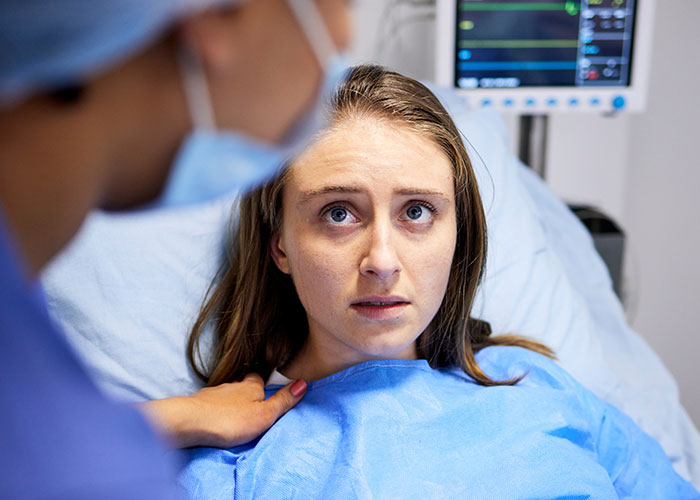 Patient in hospital bed looking fearful as nurse consoles her, depicting chilling final words doctors and nurses hear.