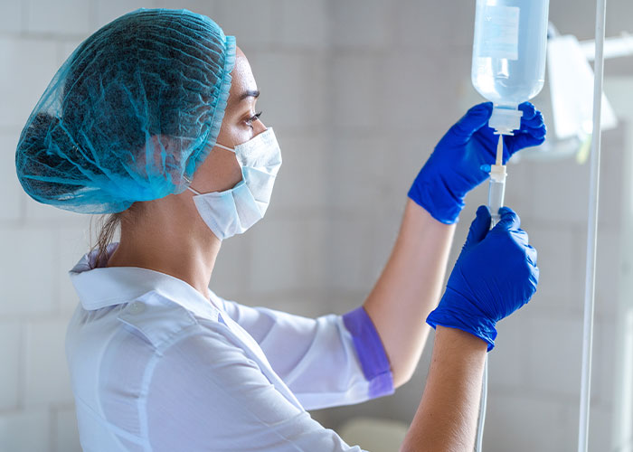 Nurse wearing mask and gloves adjusting IV drip in hospital setting, representing final words doctors and nurses heard.