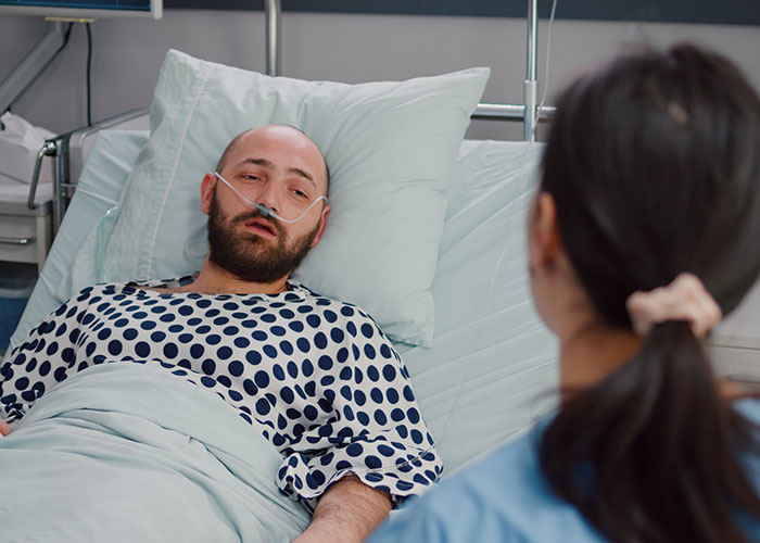 Patient in hospital bed with oxygen tube speaking to nurse, illustrating chilling final words doctors and nurses heard from patients