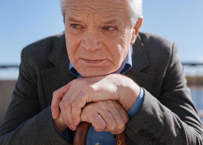 Elderly man with a cane looking thoughtfully into the distance, capturing chilling final words from dying patients.