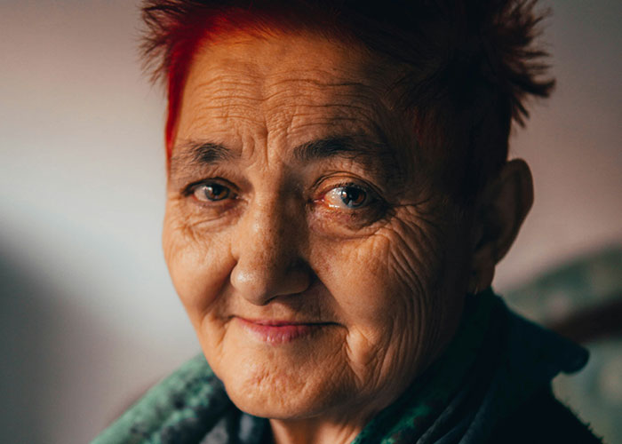 Close-up portrait of an elderly woman with red hair, conveying emotions linked to chilling final words from dying patients.