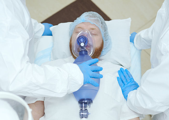 Medical staff in protective gear assisting a patient with a breathing mask, highlighting risks of patient lies in healthcare.