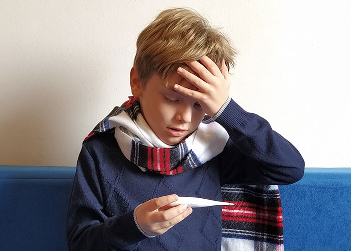 A sick boy checking his temperature with a thermometer, illustrating patient’s lie risking their health.