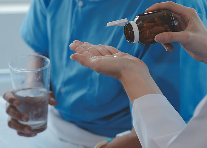 A healthcare professional handing medication to a patient highlighting risks of patient lies in medical care.
