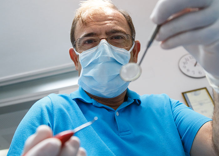 Doctor wearing mask and gloves examining a patient with dental tools, highlighting risks of patient lies in healthcare.