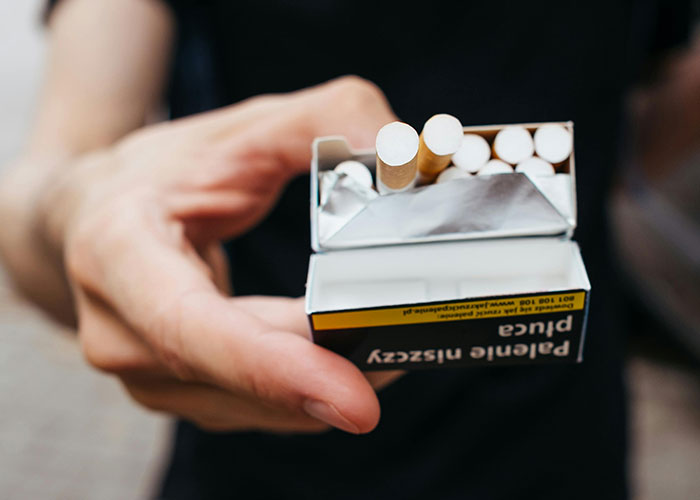 Hand holding an open pack of cigarettes, symbolizing patient’s lie that nearly cost their life in health risks.