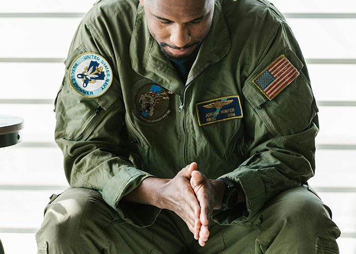 Man in military uniform sitting with hands clasped, illustrating the impact of a patient’s lie on health outcomes.