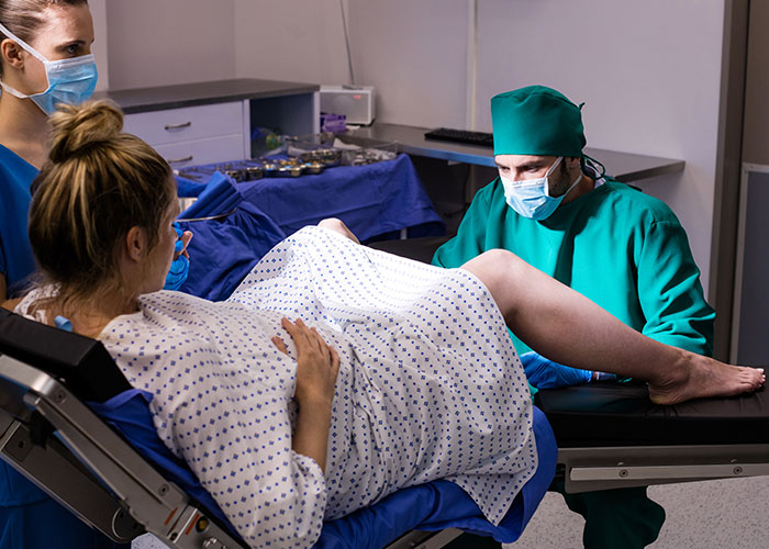 Pregnant woman in hospital delivery room with doctor and nurse, highlighting risks when patient lies to doctors.