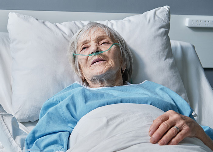 Elderly patient in hospital bed with oxygen tube, illustrating risks when a patient’s lie nearly costs their life.