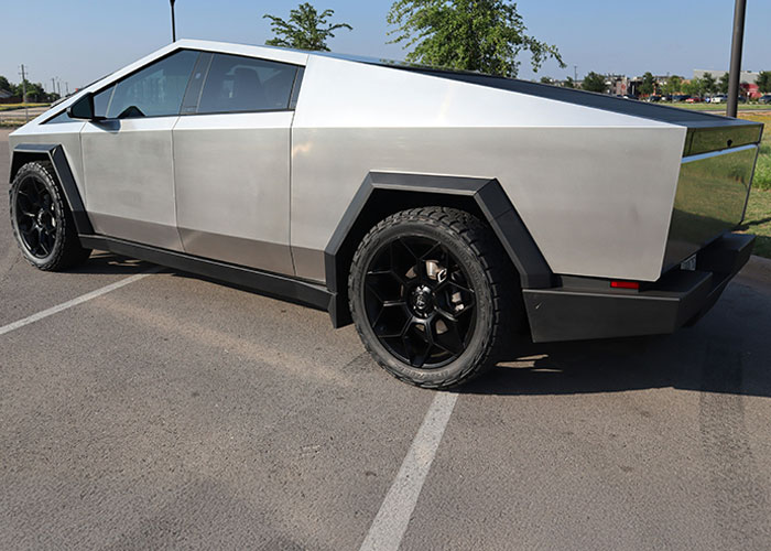 Silver futuristic truck parked on asphalt with sharp angles, highlighting the audacity of boss and late worker pay news.