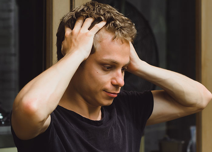 Young man frustrated and stressed as boss tells workers their pay is late after showing off new truck.
