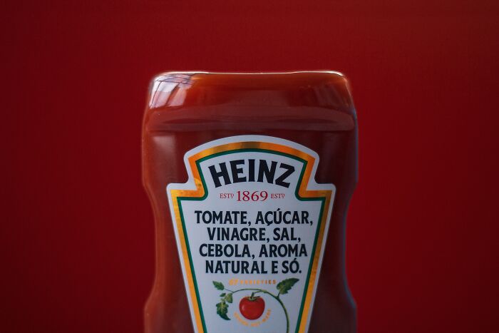 Ketchup bottle close-up against red background highlighting food price comparisons from 1980s to now.