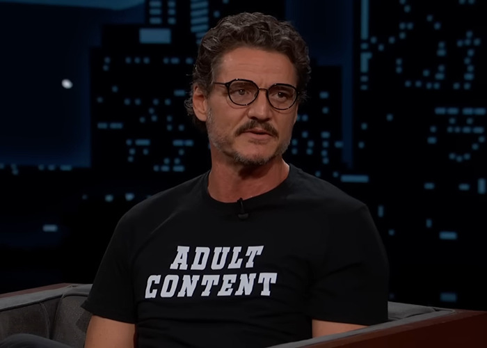 Pedro Pascal wearing glasses and adult content shirt, seated during a TV interview discussing new jaw appearance. Pedro Pascal wearing glasses and adult content shirt, seated during a TV interview discussing new jaw appearance.
