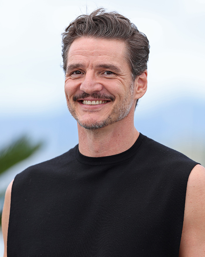 Pedro Pascal smiling outdoors wearing a sleeveless black shirt, sparking buzz about new jaw and possible plastic surgery. Pedro Pascal smiling outdoors wearing a sleeveless black shirt, sparking buzz about new jaw and possible plastic surgery.