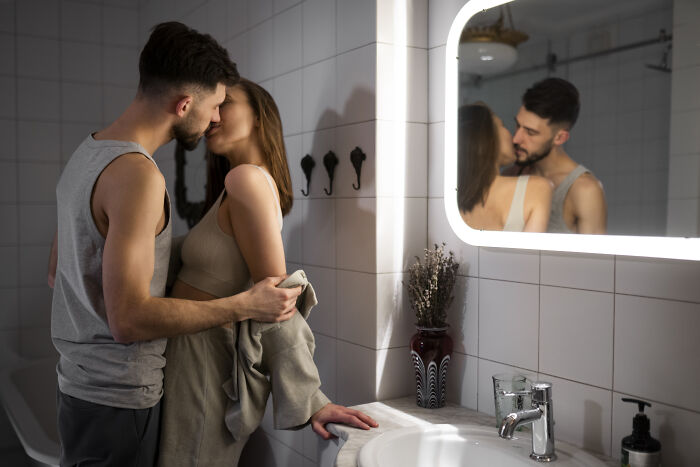 Couple sharing a romantic moment in a modern bathroom, highlighting themes people only romanticize without real experience.