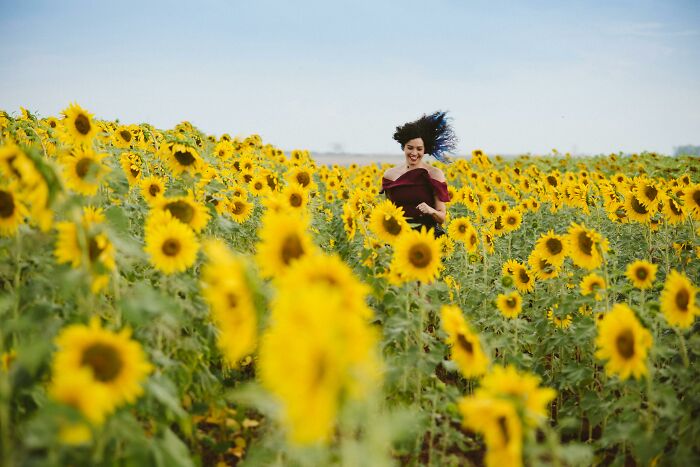 Woman running joyfully through a vibrant sunflower field, illustrating things people romanticize without real experience.