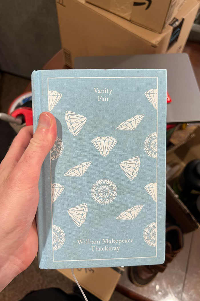 Hand holding a hardcover edition of Vanity Fair by William Makepeace Thackeray, an excellent book recommended by readers online.