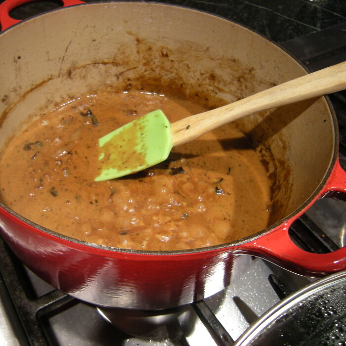 Red pot on stove with simmering sauce and green spatula, illustrating dark family secrets slowly revealed in adulthood.