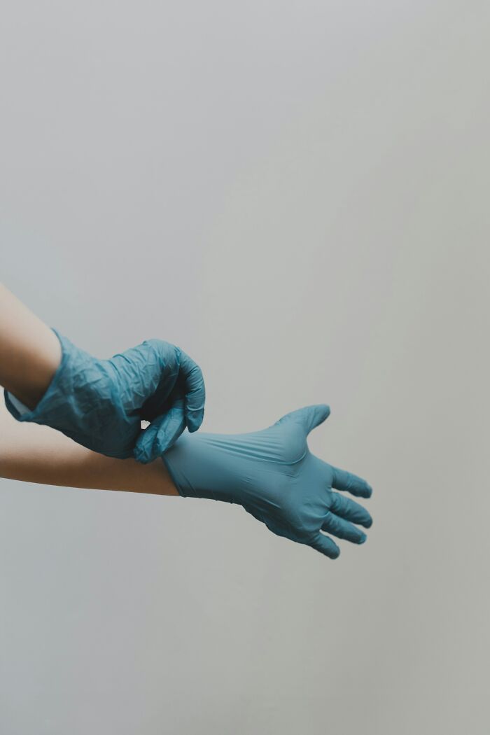 Person putting on blue gloves, demonstrating a life hack from 88 life hacks that deserve to be common knowledge.