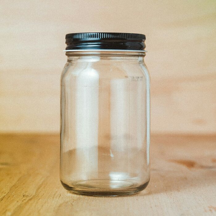 Clear glass jar with black lid on wooden surface demonstrating simple life hacks for everyday use and storage.