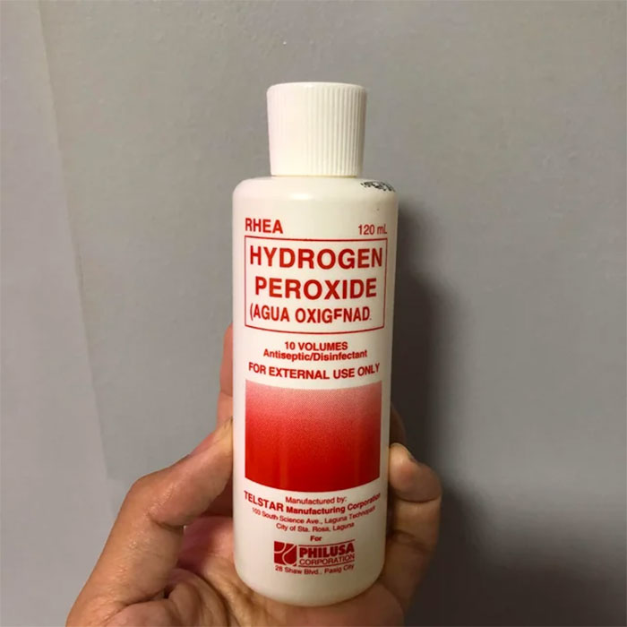 Hand holding a bottle of hydrogen peroxide disinfectant, a useful life hack for common household cleaning.