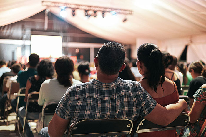 Audience seated at a dimly lit event tent, symbolizing former cult members sharing how they knew they were in a cult.
