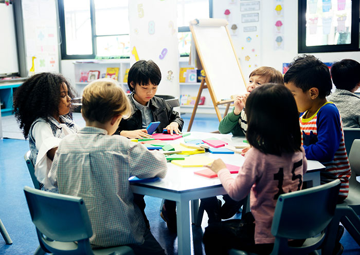 A diverse group of children sitting around a table engaged in collaborative learning and creative activities indoors.