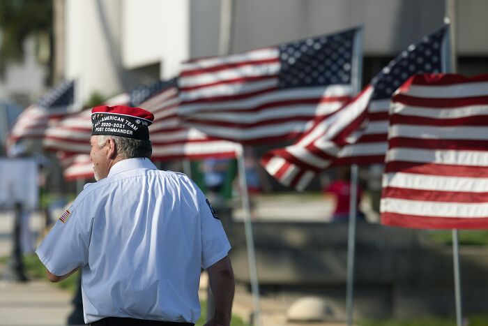 Veteran walking past a row of American flags outdoors, symbolizing solemn moments linked to disturbing confessions.