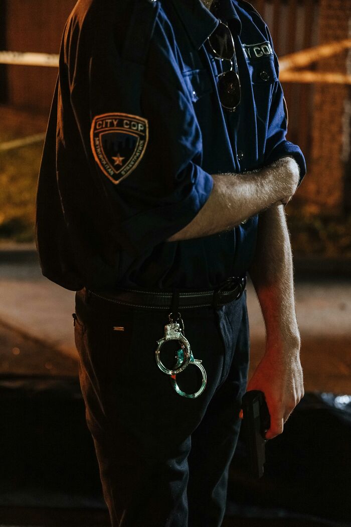 Police officer in uniform holding a gun with handcuffs on belt, representing disturbing confessions in casual settings.