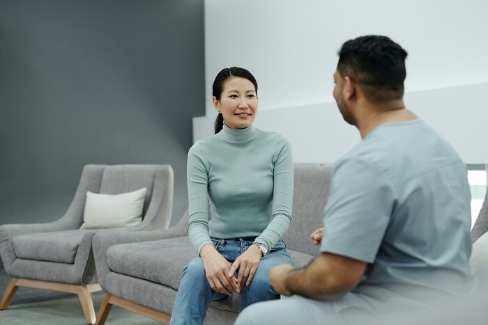 A woman and a man having a conversation in a modern room, illustrating microfeminisms supporting women.