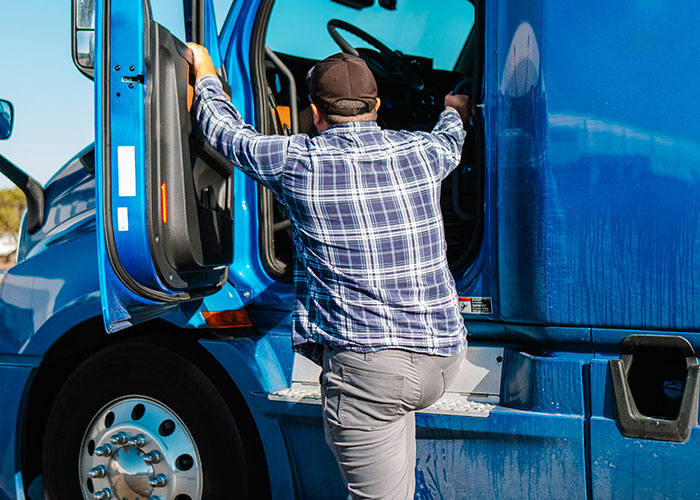 Man wearing a cap and plaid shirt climbing into a blue truck, illustrating exposure of cheating partners stories.
