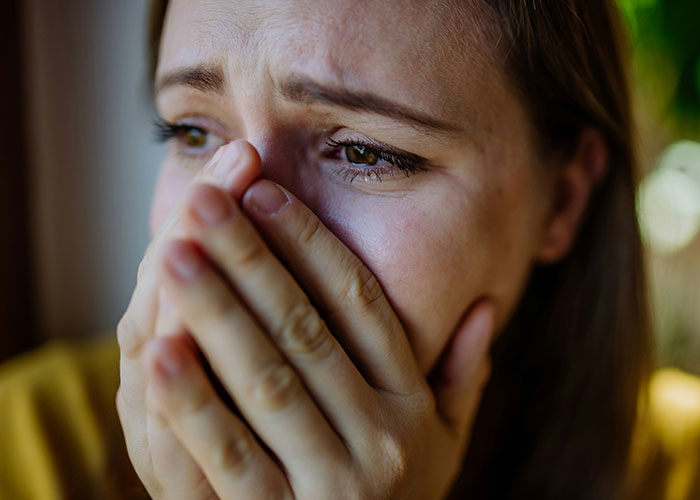 Close-up of a distressed woman covering her mouth, reflecting the emotional impact of cheating partners being exposed.
