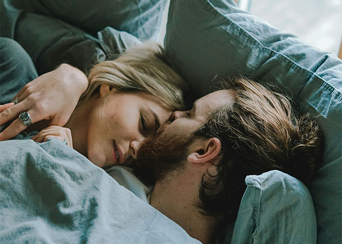 A couple lying closely in bed, symbolizing relationships and revealing cheating partners in intimate settings.