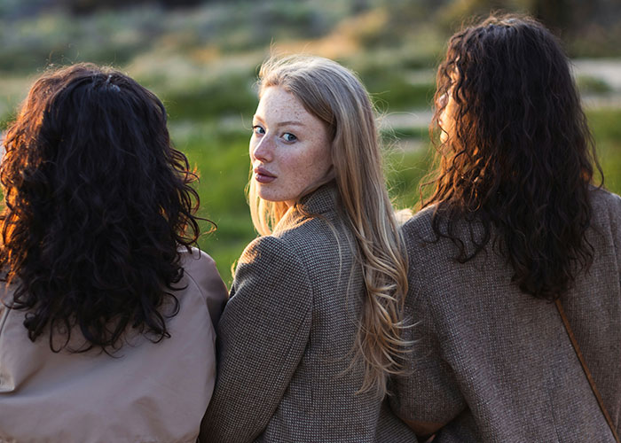 Three women outdoors with one turning to look back, illustrating stories about exposing cheating partners and betrayal.