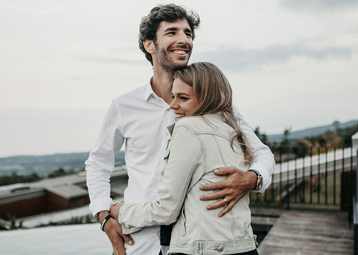Couple embracing outdoors on a terrace, symbolizing trust and emotions in stories about cheating partners revealed.