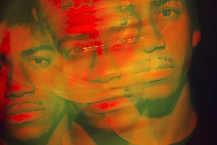 Abstract triple exposure of a young man's face with eerie red and green tones, evoking resurrection and spooky tales themes.