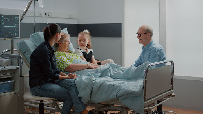 Family visiting an elderly patient in hospital bed, sharing a heartfelt moment about life, death, and resurrection stories.
