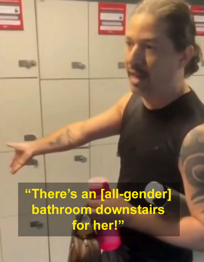 Man with tattoos at gym locker room gesturing, physically blocking a woman from gym bathroom access.