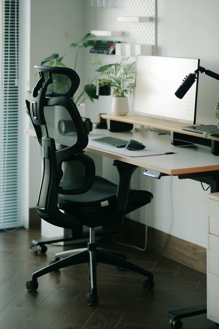 Ergonomic office chair and clean workspace with desktop computer, plants, and accessories improving quality of life.