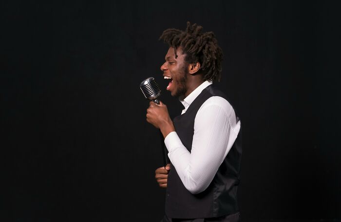 Man passionately singing into vintage microphone, showcasing talent in songs you&rsquo;ve definitely heard before challenge.