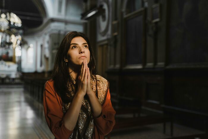 Young woman praying inside a church illustrating examples of the placebo effect in real life related to religion and beliefs