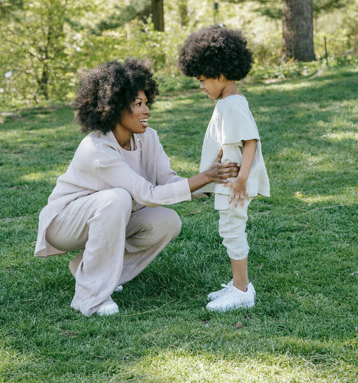 Woman teacher kneeling on grass talking to a child outdoors showing unhinged but actually work teaching moments.