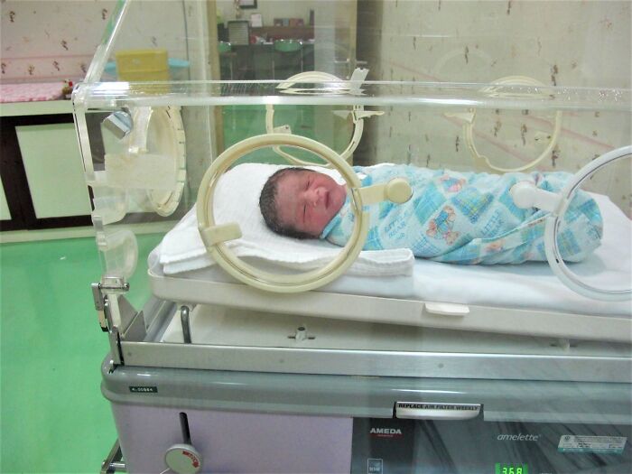 Newborn baby wrapped in a blue blanket inside a hospital incubator, an interesting find shared by medical professionals.