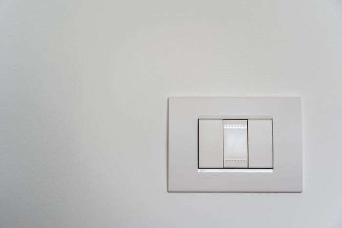 White light switch panel on a plain wall, illustrating the concept of excessively lazy actions shared by people.